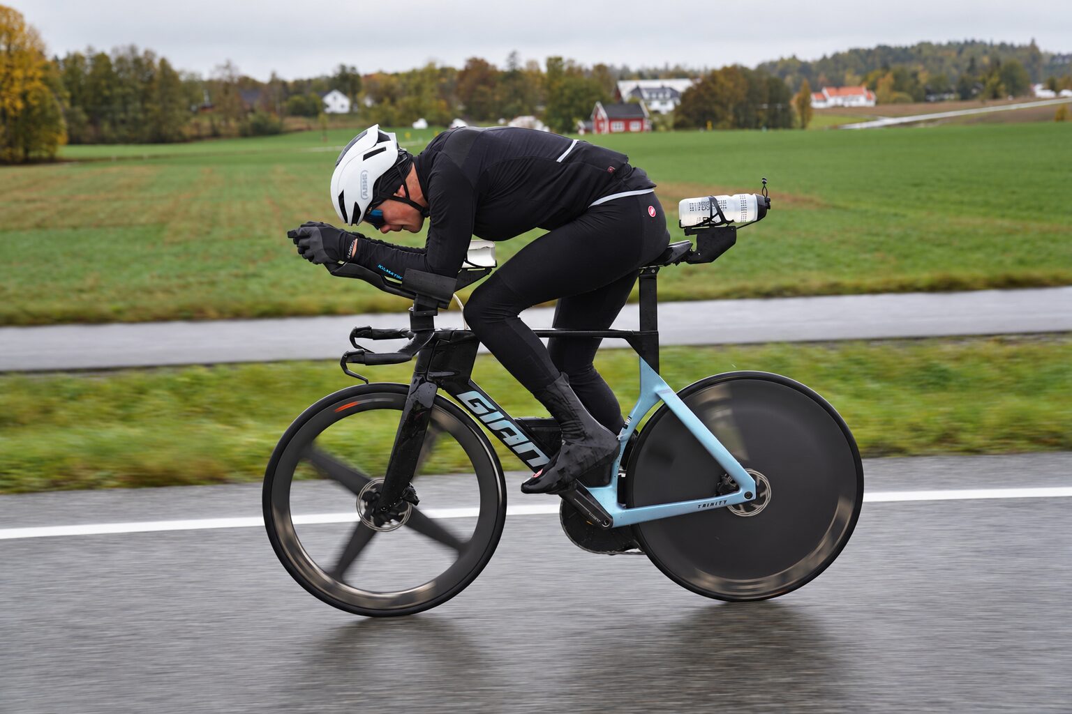 Sigurd on his time-trial bike in aero position on a wet Norwegian country road